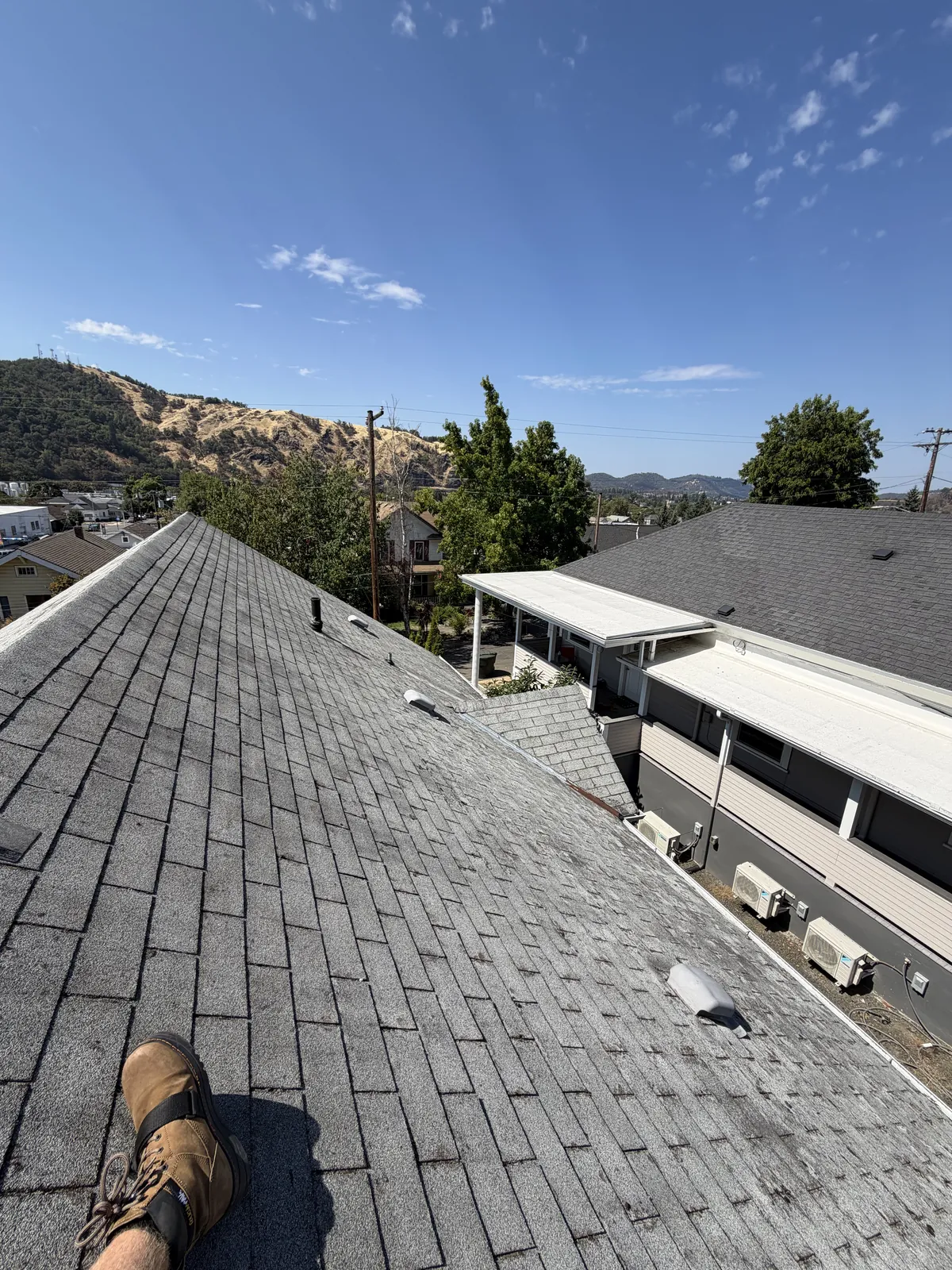 Cleaned asphalt shingle roof running from ridge to eave with the Rogue Valley hills behind it, Southern Oregon