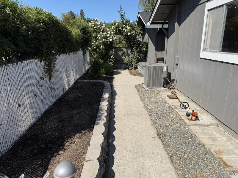 The same side yard bed stripped back to clean soil with the walkway swept after a Hilltop Landscaping cleanup in Southern Oregon