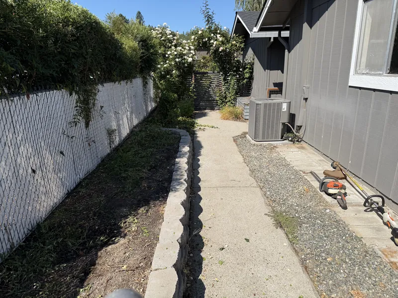 Weedy side yard planting bed along a chain link fence before Hilltop Landscaping cleared it, Southern Oregon