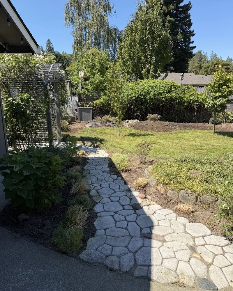 Backyard flagstone path fully exposed with mulched beds and a mowed lawn after Hilltop Landscaping restored the yard in Southern Oregon
